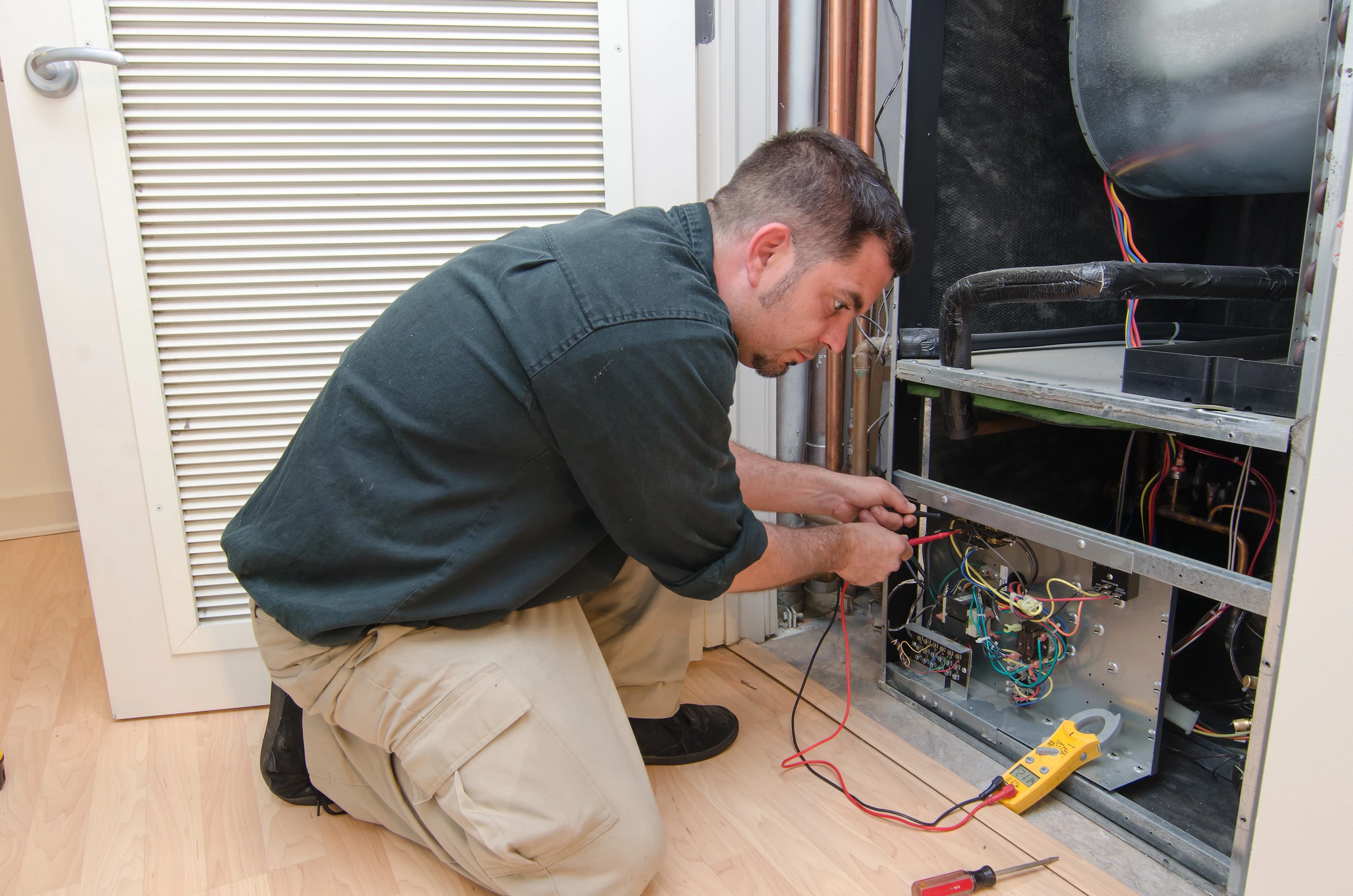 HVAC technician servicing equipment with diagnostic tools