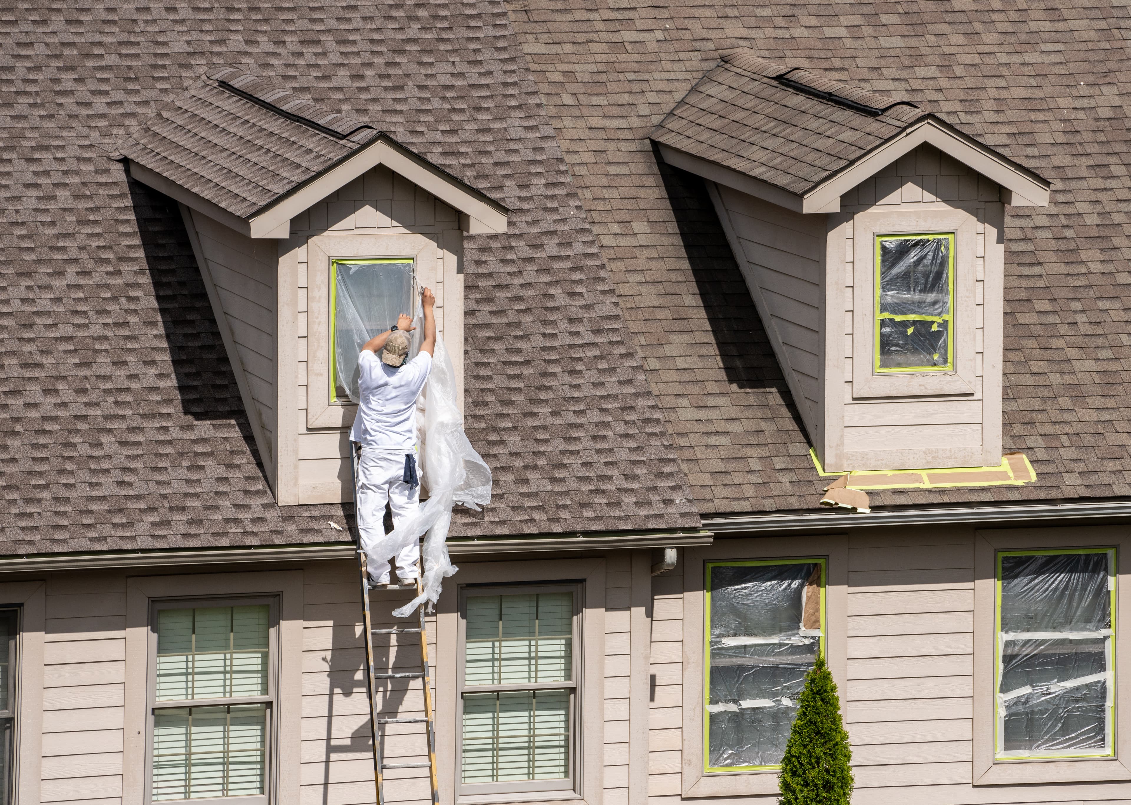 Worker on a ladder doing roofline installation prep