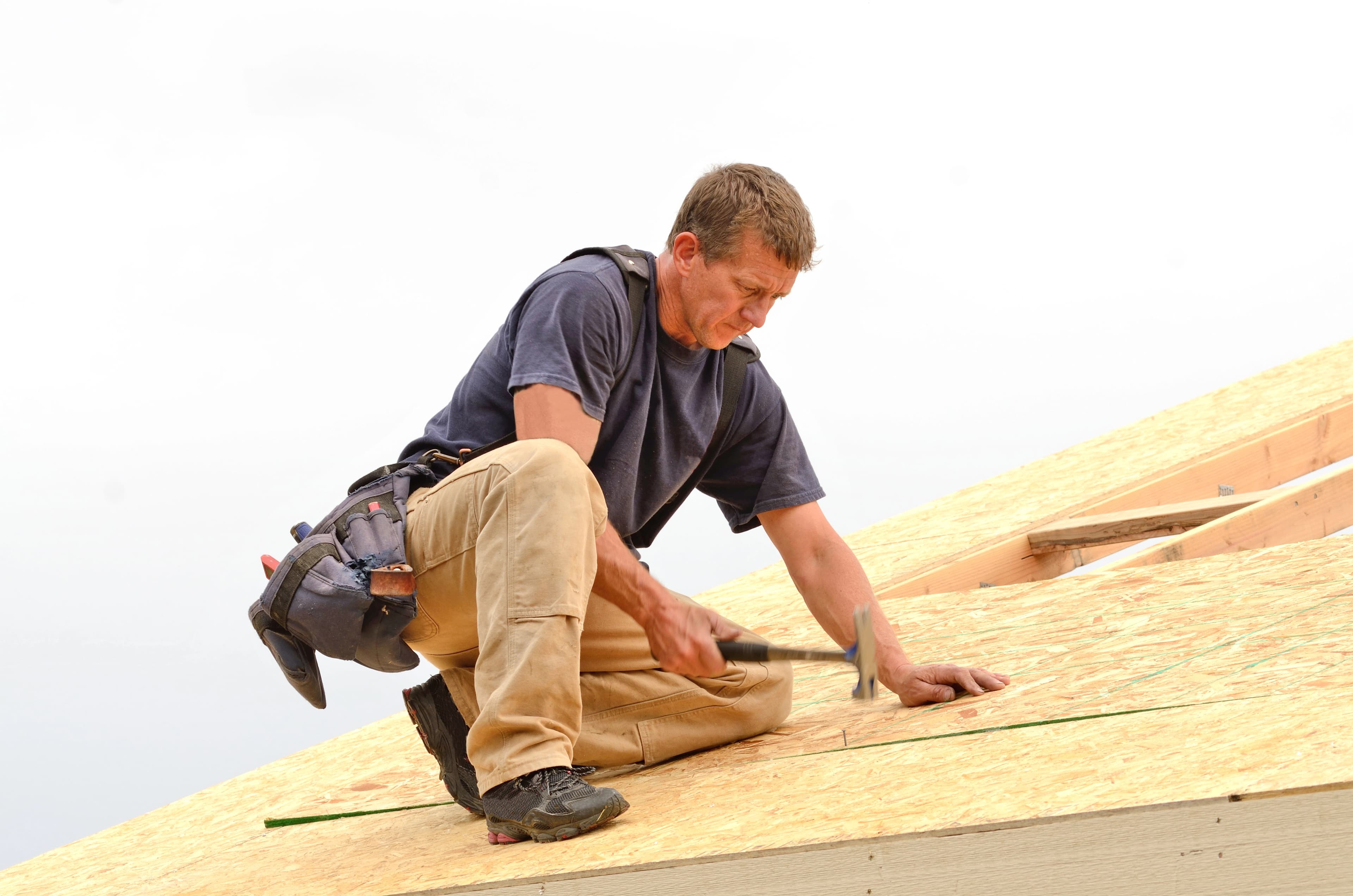 Roofer installing shingles on a roof deck
